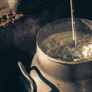 Curd being churned in a steel pot, butter rising to the top